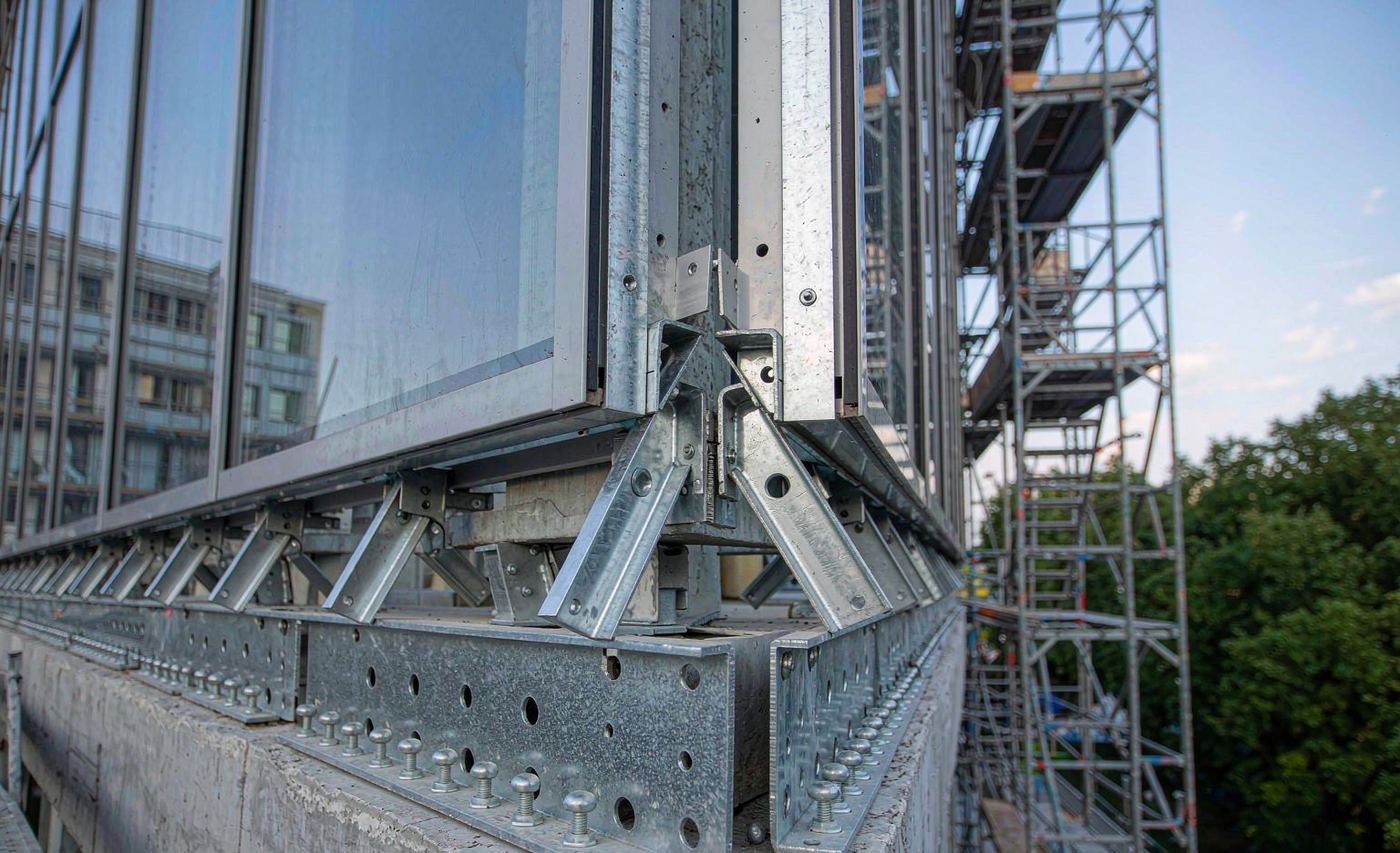 Galvanized embedded plates on a concrete slab edge supporting a glass curtain wall frame