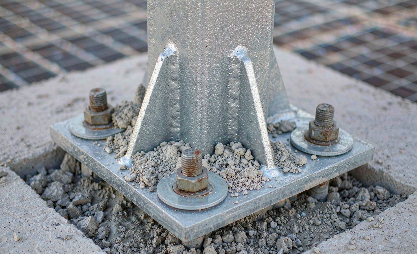 Steel column base plate anchored to concrete foundation with anchor bolts and nuts