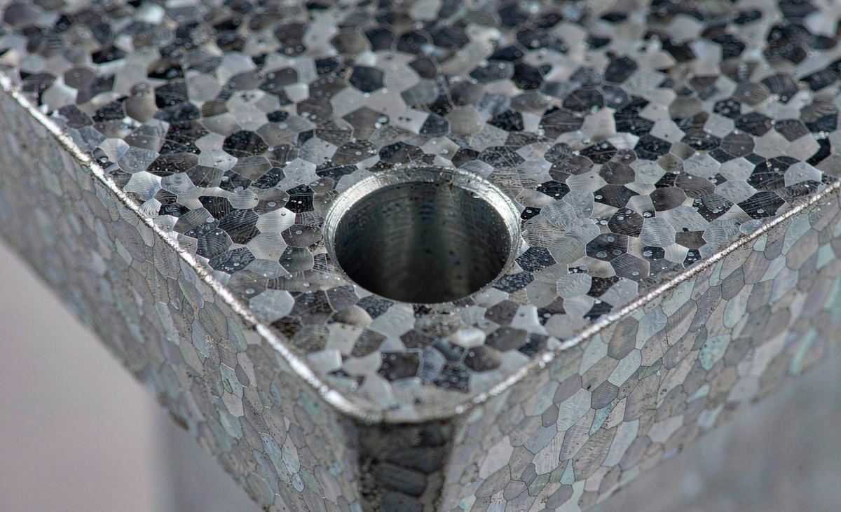 Close-up of pre-drilled anchor bolt hole and chamfered edge on galvanized base plate