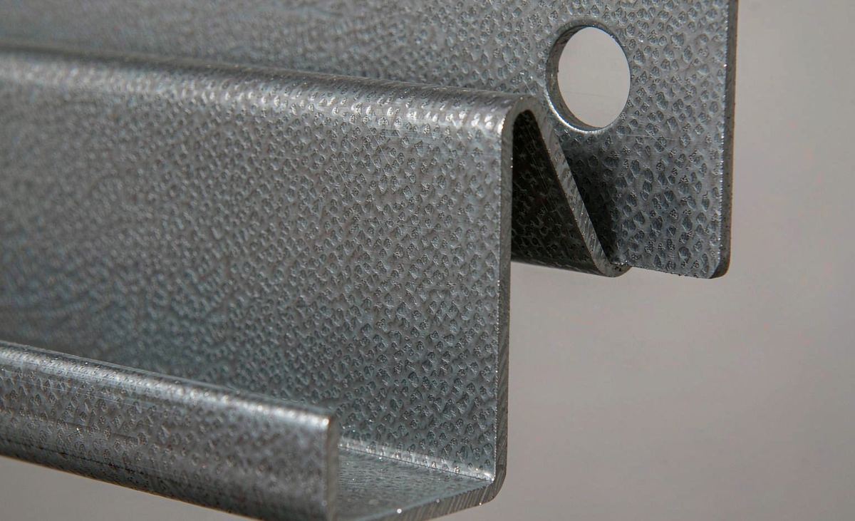 Macro view of a pre-punched hole and roll-formed edge on a galvanized steel C-channel